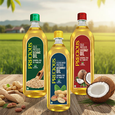 Three bottles of 'Precious' brand oils on a wooden surface with a natural background